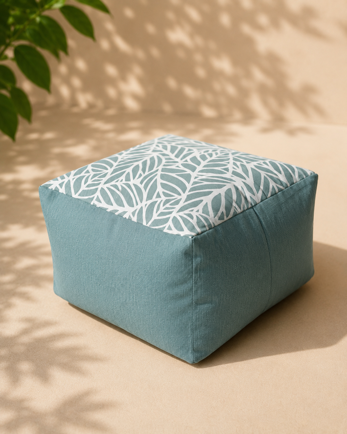 Blue ottoman with white leaf pattern on a beige background