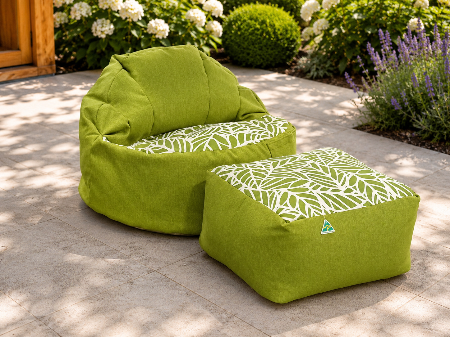 Green bean bag chair and ottoman with leaf pattern on a stone patio