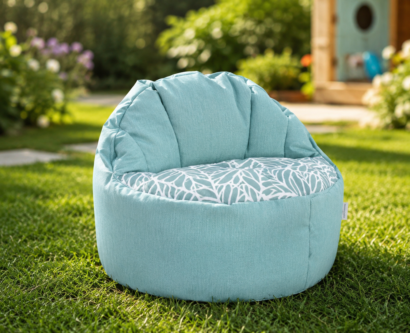 Light blue bean bag chair with a leaf pattern on a grassy area