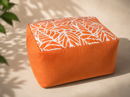 Orange ottoman with a white leaf pattern on a beige surface