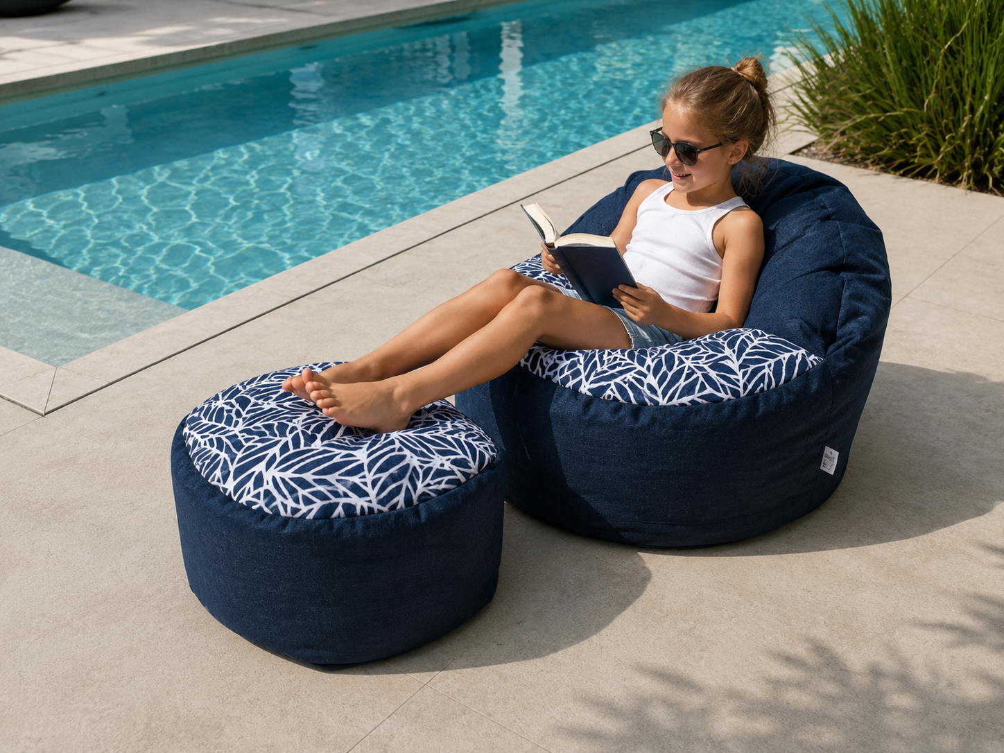 Woman reading a book on a navy bean bag chair by a poolside