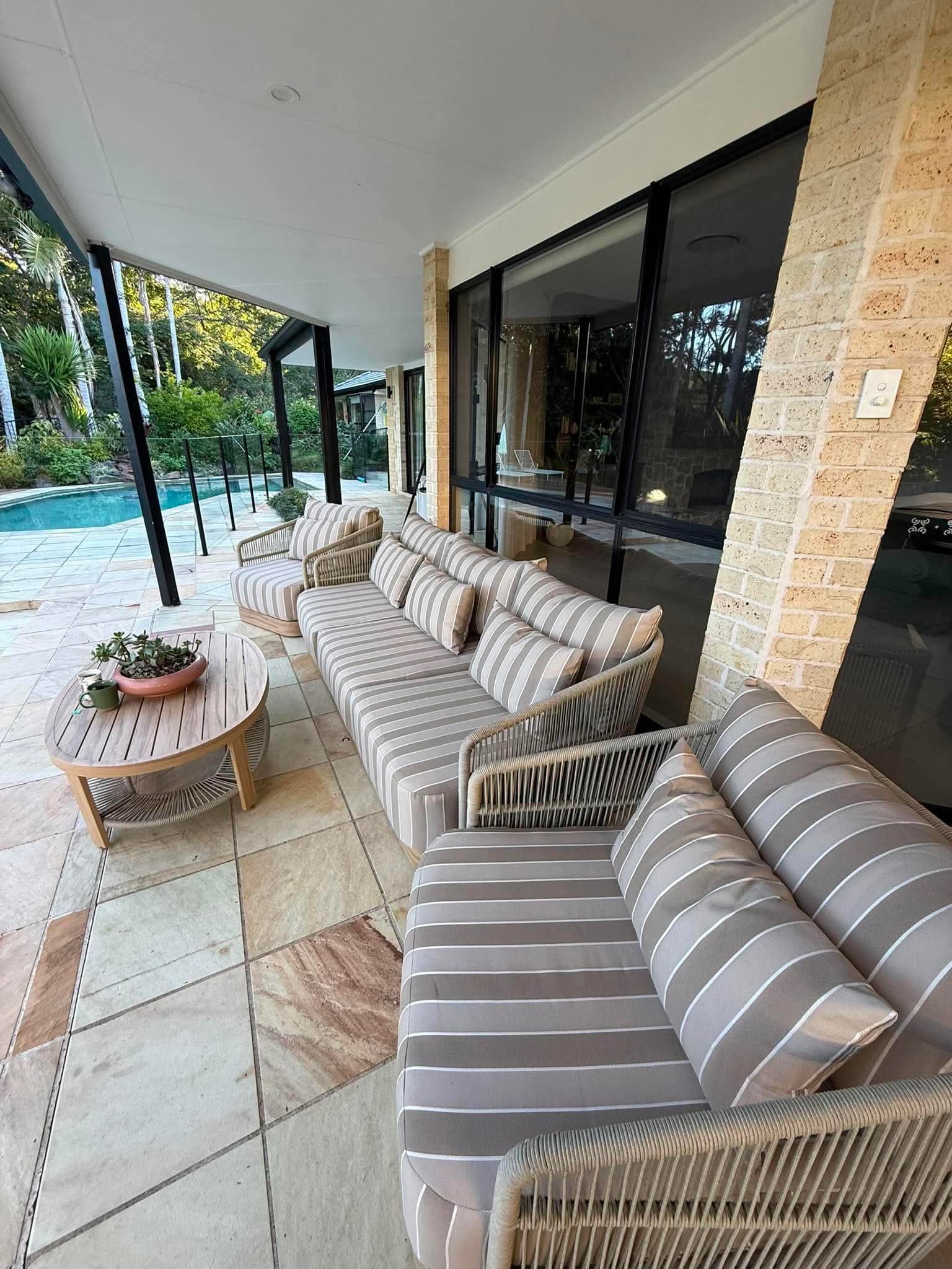 Outdoor patio with striped sofa, coffee table, and pool view