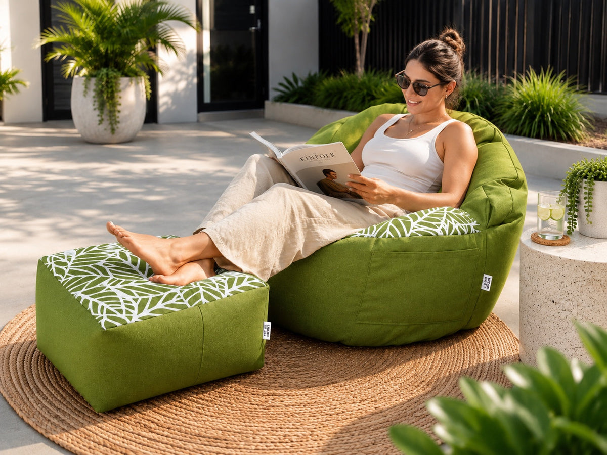 Woman relaxing outdoors on a Lazy Beanz Island Palm Green adult bean bag and square ottoman set