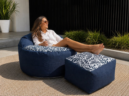 Woman relaxing outdoors on a Lazy Beanz Midnight Reef adult bean bag and square ottoman set