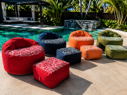 Lazy Beanz adult outdoor bean bags and matching ottomans in four colours arranged beside a swimming pool